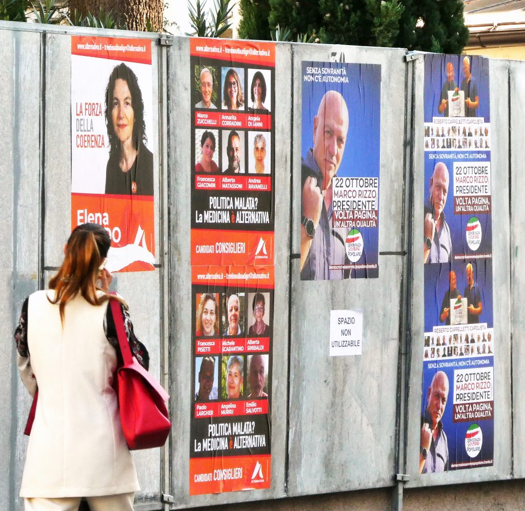 Una donna guarda i manifesti elettorali